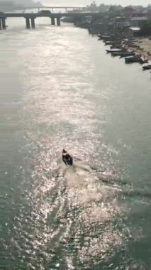 Güneşli bir günde Vietnam 'daki köprünün yakınındaki adalar arasındaki balıkçı teknesini takip eden insansız hava aracı FullHD Dikey