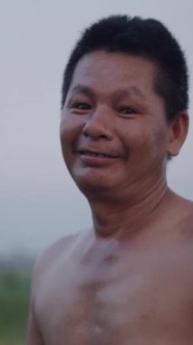 Gün boyunca kameraya el sallayan ve gülümseyen terli Vietnamlı bir çiftçinin portresi.