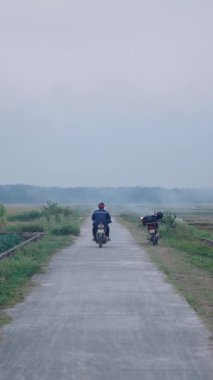 Çiftçi, Vietnam 'da dar bir yol boyunca küçük bir motosikletle ekin tarlasına gidiyor.