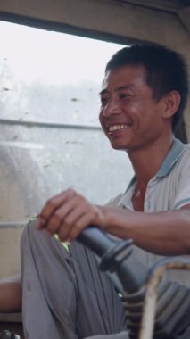 Vietnam 'da kameraya gülümseyen yaşlı bir vinci kontrol eden Asyalı bir çocuğun portresi.