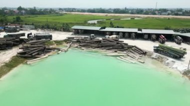 Vietnam 'da yapay bir gölün yanında ağaç gövdeleri ve beton karıştırıcı kamyonların depolandığı sanayi bölgesi - 4K Yatay