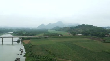 Vietnam ormanındaki vadiyle dağlar arasındaki büyük nehri geçen uzun bir köprü - 4K Yatay
