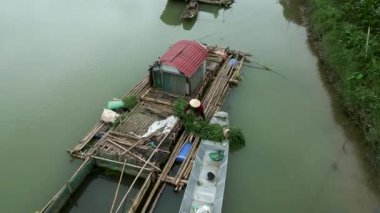 Vietnamlı kadın çiftçi teknesini nehrin kıyısındaki barakanın yanında boşaltıyor - 4K Yatay