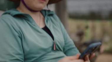 Vietnamese 'li genç bir kadının portresi akıllı telefonunun ekranına bakıyor iş arasında oturuyor - 4K Yatay