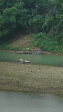 Balıkçı küçük teknesini Vietnam 'daki nehir kıyısının yakınındaki küçük bir adaya park ediyor.