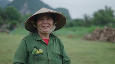 Vietnamlı bir ormandaki büyük bir şapkayla kameraya bakıp gülümseyen Asyalı kadınların portresi - 4K Yatay