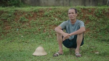 Vietnam 'da hareket etmeden şapkasının yanında oturan Asyalı çobanlar dinleniyor - 4K Yatay