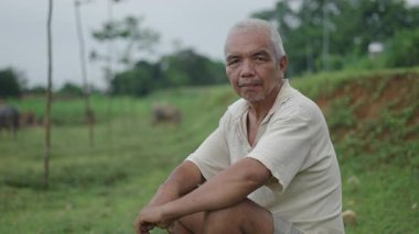 Asyalı olgun bir adam sakin ve rahat bir şekilde Vietnam 'da bir ormanda kameraya bakıyor - 4K Yatay