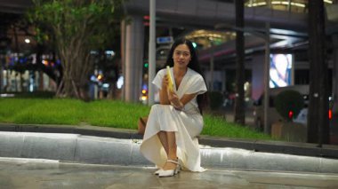 Sıska Asyalı kız, uzun saçlı, gülümseyen ve elinde tablet tutarken kameraya bakan - 4K Yatay