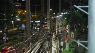 Bangkok Tayland 'da bir bulvarda geceleyin kablolara ve elektrik direklerine yağmur yağıyor - 4K Yatay