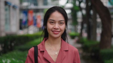 Şehir parkında gülümseyen genç Asyalı kadın - 4K Yatay