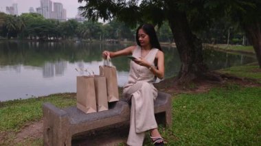 Parkta alışveriş yaptıktan sonra yeni sarı tişört gösteren mutlu müşteri - 4K Yatay