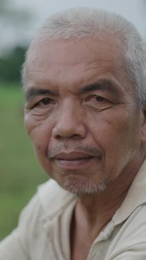 Kameraya dik dik bakan kısa beyaz saçlı olgun Asyalı adamın portresi.