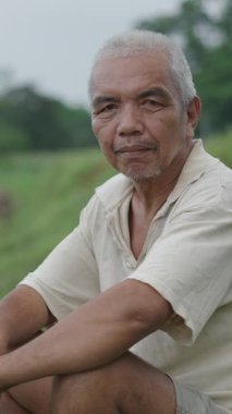 Asyalı olgun bir adam sakin ve rahat bir şekilde Vietnam 'daki bir ormanın kamerasına bakıyor.