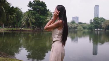 Güzel genç bir kadın göl kenarında dans ediyor. Huzurlu bir parkta. 4K Yatay.