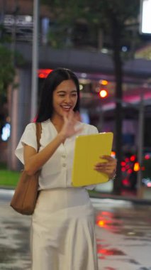 Gece Bangkok 'ta kameraya doğru yürüyen Asyalı kız tabletle video görüşmesi yaparken FullHD Dikey