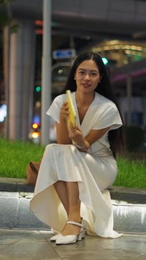 İnce Asyalı kız, uzun saçlı, gülümseyen ve elinde tabletle kameraya bakan FullHD dikey.