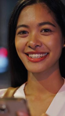 Bangkok Tayland 'da geceleri kameraya bakarken düz saçlı, esmer Asyalı kızın yakından çekilmiş yüzü FullHD dikey