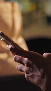 Beyaz ipek bluzlu genç bir kadın akıllı telefonuyla ekrana dokunarak etkileşime giriyor.