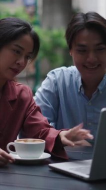 Asyalı erkek ve kadın iş stratejilerini açık kafede tabletle tartışıyor.