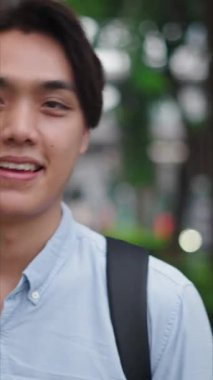 Dışarıda gülümseyen ve kahve içen genç Asyalı öğrenci - FullHD Dikey