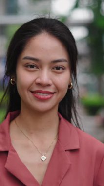 Şehir parkında gülümseyen genç Asyalı kadın - FullHD Dikey