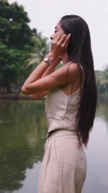 Genç ve güzel bir kadın, huzurlu bir parkta, gölün kenarında dans ediyor.