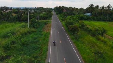 Motosikletçi kırsal alanda uzun düz bir yolda gidiyor - 4K Yatay