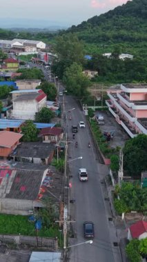 Tayland 'ın kırsal kesiminde, dağların arasındaki FullHD dikey bir alanda havadan gelen yolu takip eden insansız hava aracı.