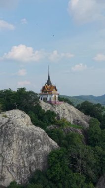 Tayland ağaçlarının arasındaki kayalık bir dağın tepesindeki küçük Budist tapınağı.