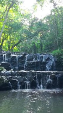 Şelaleler üzerinde uçan insansız hava aracı ve ağaçlar ve dağlar arasında ormandaki nehir.