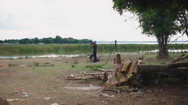 Tayland 'da köpeğiyle nehir kıyısında pis bir yerde çalışan fotoğrafçı - 4K Yatay