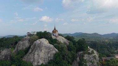 Tayland ağaçlarının arasındaki kayalık bir dağın tepesindeki küçük Budist tapınağı - 4K Yatay