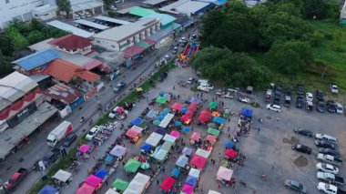 Ağaçların yanındaki otoyolun yakınındaki geniş kırsal bir açık hava pazarının havadan görünüşü - 4K Yatay