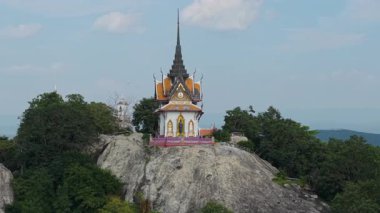 Tayland 'da bir dağda büyük bir kayanın üzerinde büyük bir Budist tapınağının etrafında uçan İHA - 4K Yatay