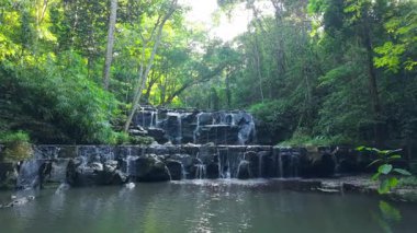 Şelaleler üzerinde uçan insansız hava aracı ve ağaçlar ve dağlar arasında ormandaki nehir - 4K Yatay