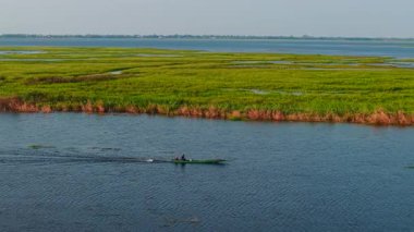 İki balıkçı, geleneksel ahşap bir tekneyle sakin sularda yüzerler - 4K Yatay
