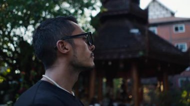 Tayland 'daki Budist tapınaklarının güzelliğine hayran olan gözlüklü Latin bir çocuğun yakın çekimi. 4K Yatay