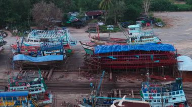 Dronesold 'un köhne balıkçı tekneleri kirli bir tersanede sıralanmış. 4K Yatay.