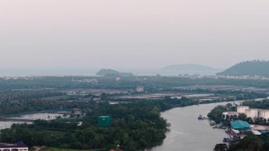 Gün batımında denize dökülen bir nehrin yanında yakıt tankları olan sanayi bölgesi - 4K Yatay
