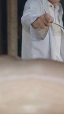 Bir yavru domuz közlerin yakınında bir çemberde kızarırken bir aşçı Vietnam 'da cildini yağla fırçalar.