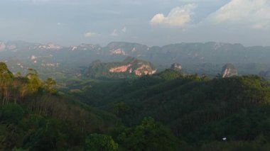 Yeşil yemyeşil ormanlarla kaplı bir dağ sırasının panoramik görüntüsü - 4K Yatay