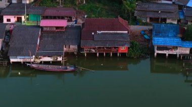 Geleneksel Tayland stilt evleri insansız hava aracı görüşünden sakin bir nehir hizasında - 4K Yatay
