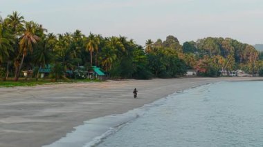 Motosikletçi Chumphon, Tayland 'daki Aao thung Makham plajı boyunca huzurlu bir gezinti yapıyor. 4k yatay.