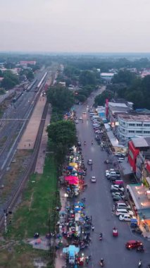 Tedarikçileri ve trafiği gösteren küçük bir köydeki tren raylarının yanındaki sokak pazarı FullHD Dikey