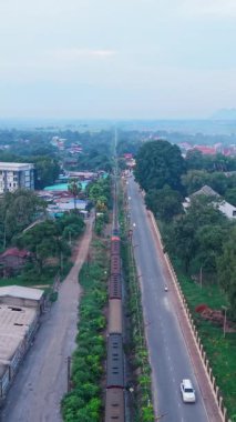 Yolun yanındaki küçük bir Asya köyünden geçen yük treni FullHD Dikey