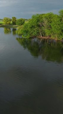 İnsansız hava aracı Pasak Chonlasit Gölü 'nün suları üzerinde uçuyor, etrafını çevreleyen sessiz yolun yanında, FullHD Dikey