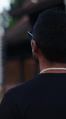 Koyu tenli bir Latin çocuk Tayland 'daki büyük bir Budist tapınağının önünde yavaşça yürüyor. Tam HD Dikey