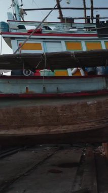 Büyük ahşap bir balıkçı teknesi, FullHD Dikey Tamirat yapılan bir tersanenin bloklarında duruyor.