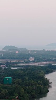 Gün batımında denize dökülen bir nehrin yanında yakıt tankları olan sanayi bölgesi FullHD Dikey